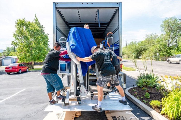 Happy Home Moovers crew loading protected furniture into a moving truck with professional equipment
